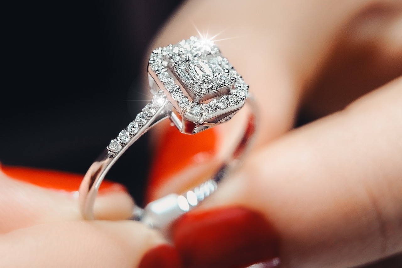 A close-up of a bride-to-be holding a stunning side stone engagement ring.