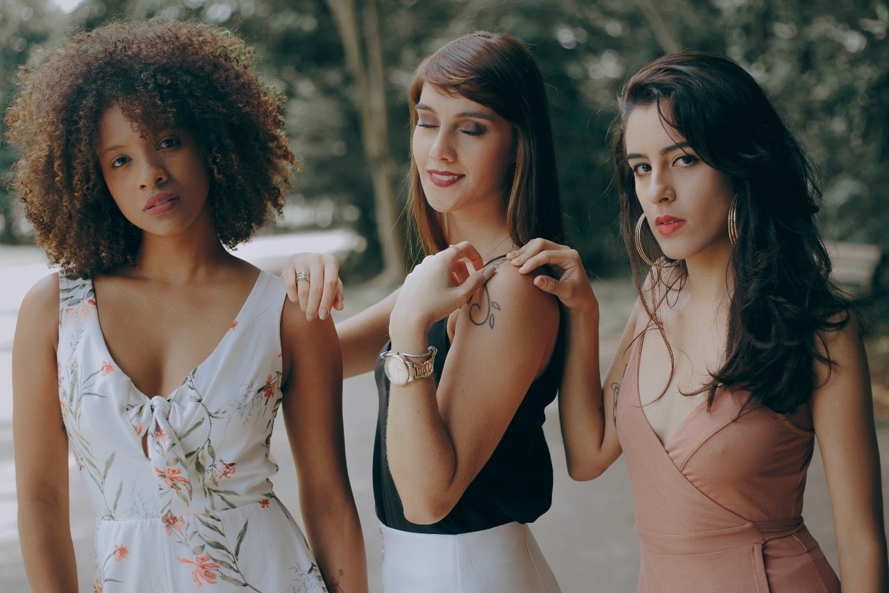 three ladies standing next to each other wearing luxury watches