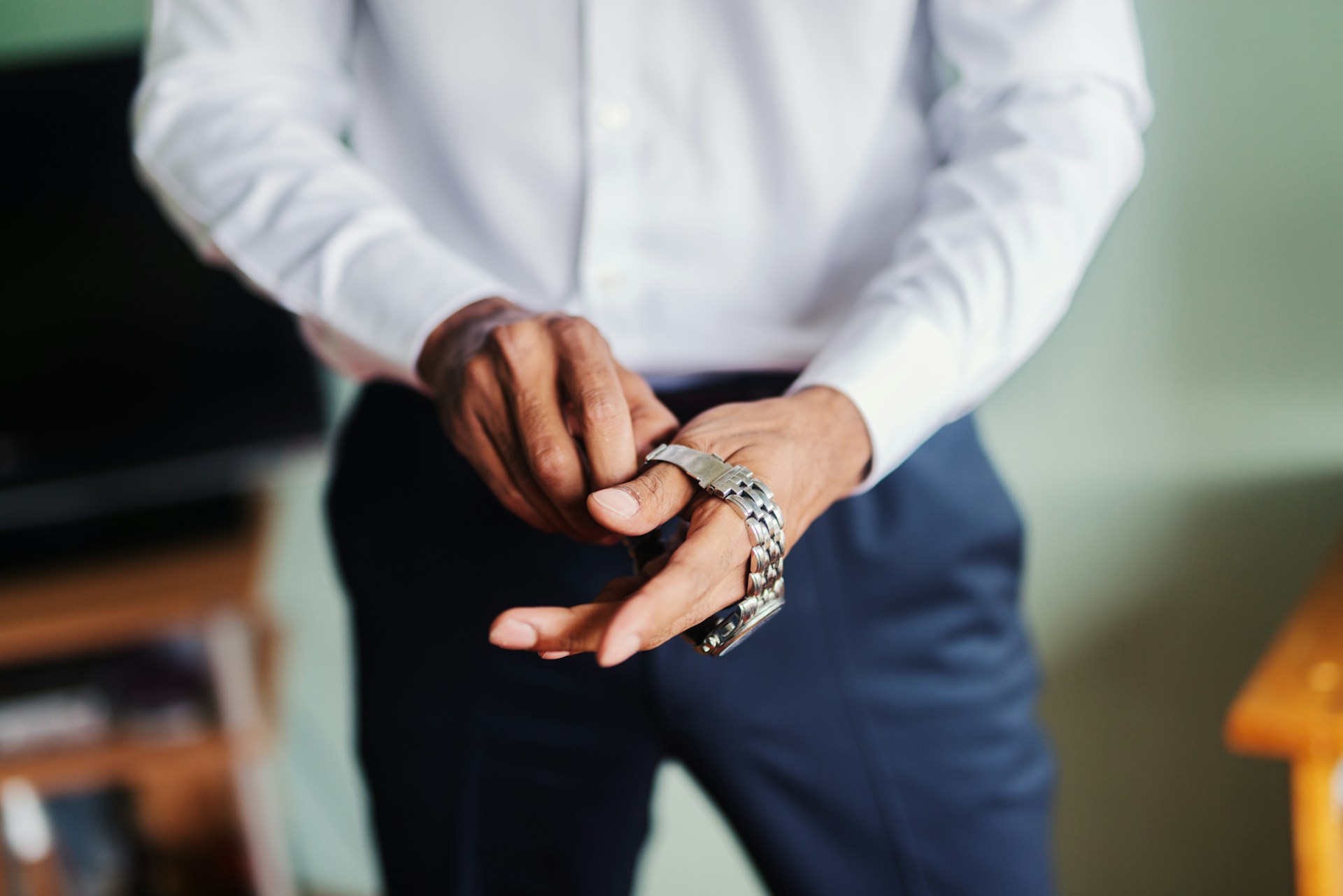 a man in business clothes putting on a luxury watch