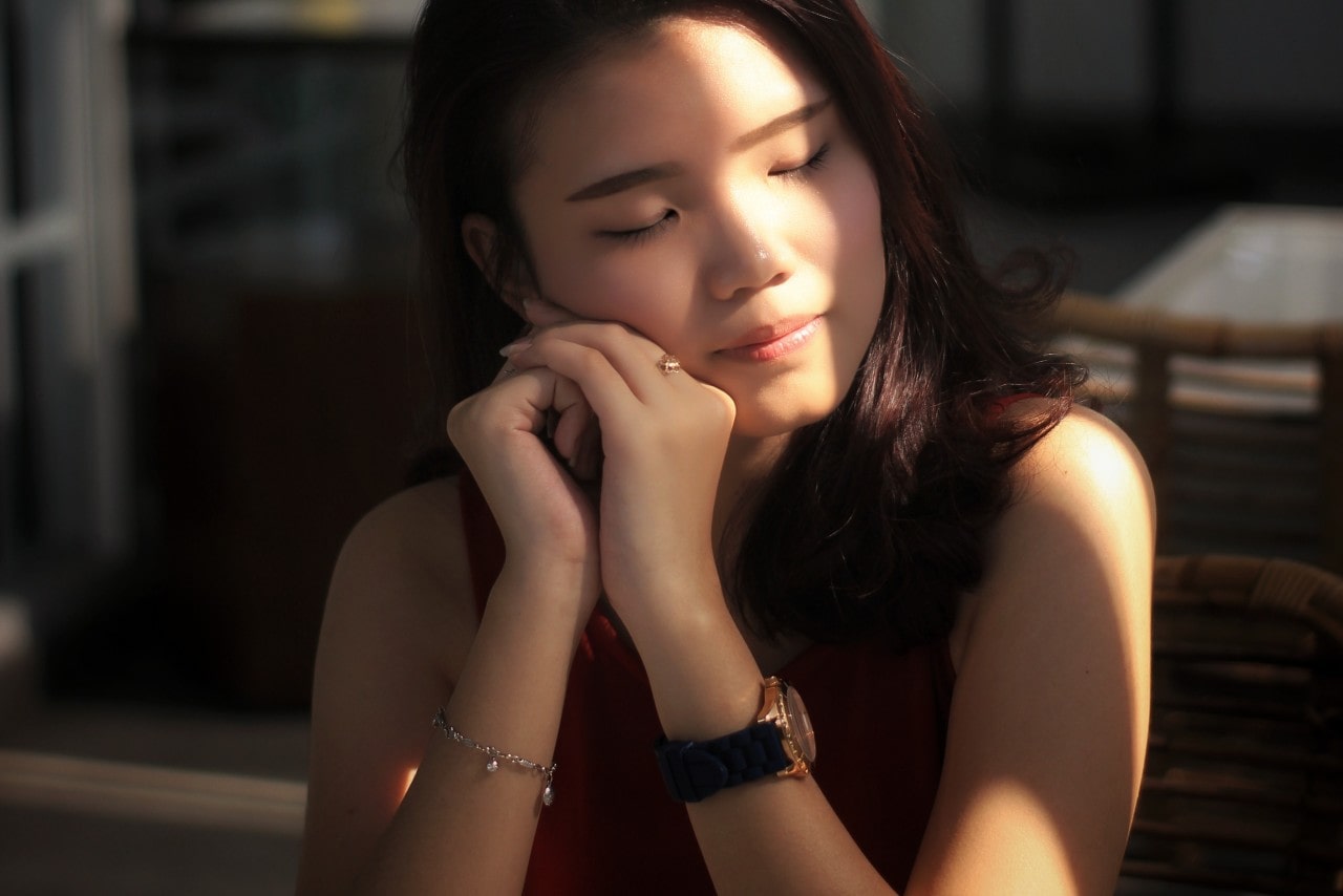 Woman sitting at a table in the sunlight wearing jewelry and a watch