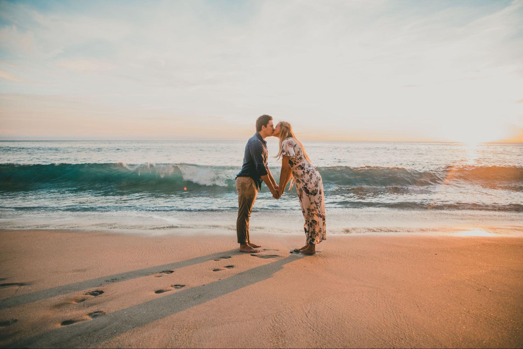 Man and woman kissing on the beach.