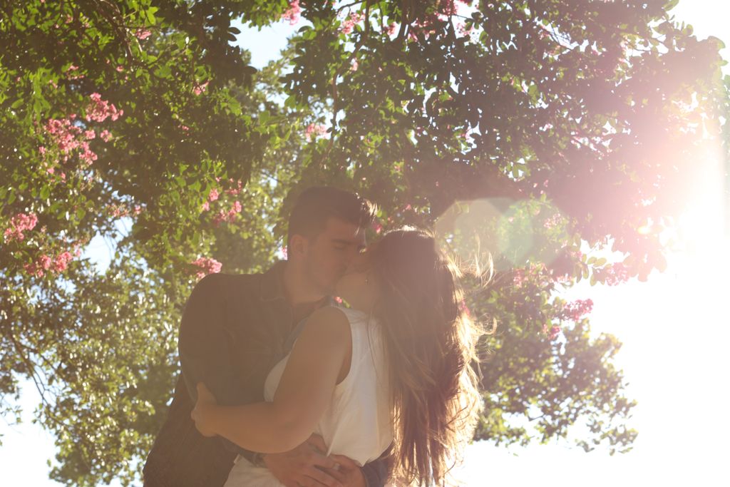 Women and a man kissing outside in the sun.