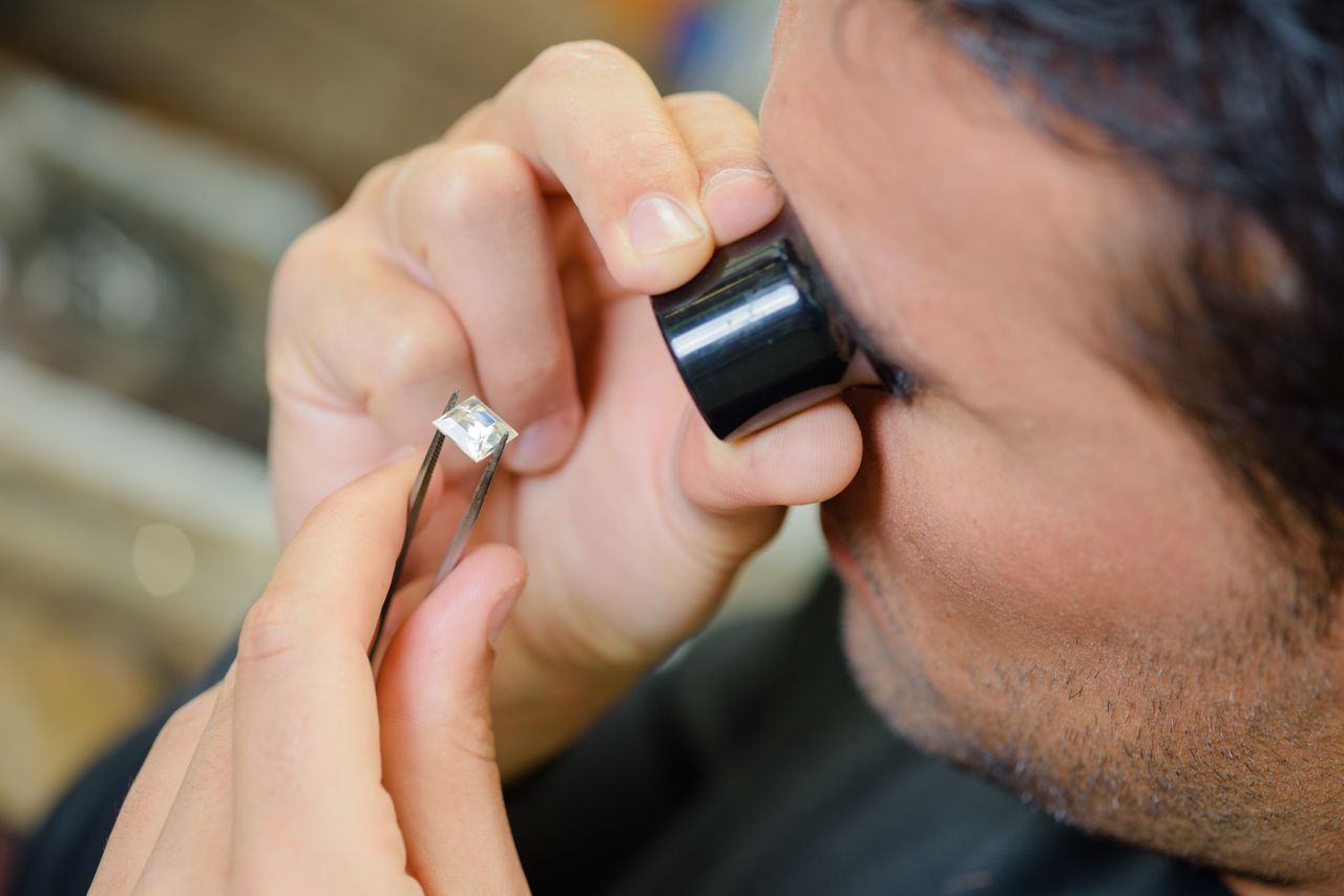 Gemologist inspecting a princess cut diamond.