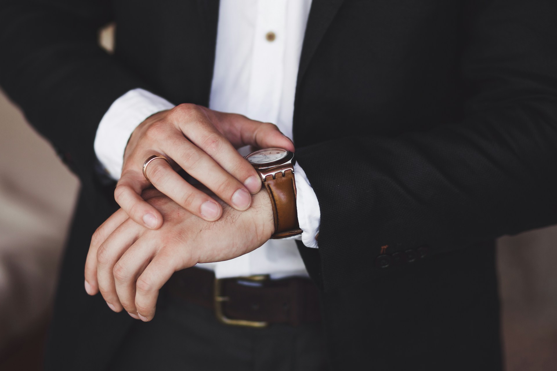 a torso shot of a man in a suit checking his wrist watch