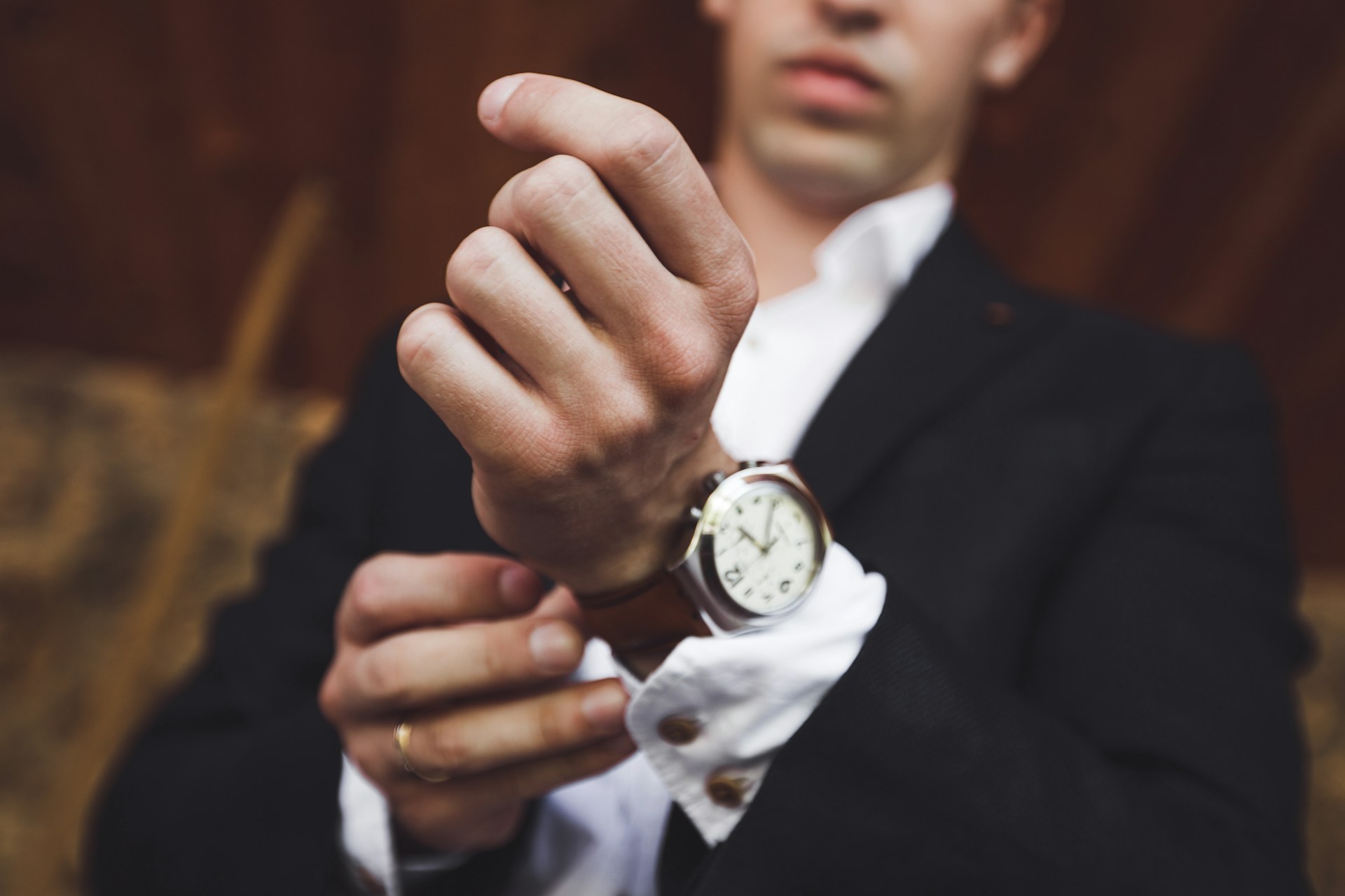 an image of a man in a suit putting on a simple dress watch