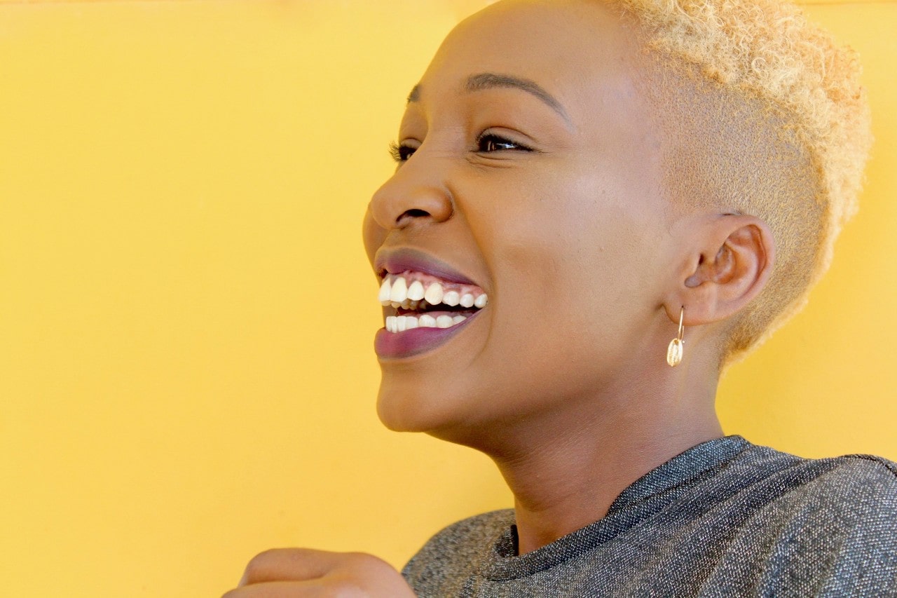 lady smiling and wearing fashion earrings on a yellow background