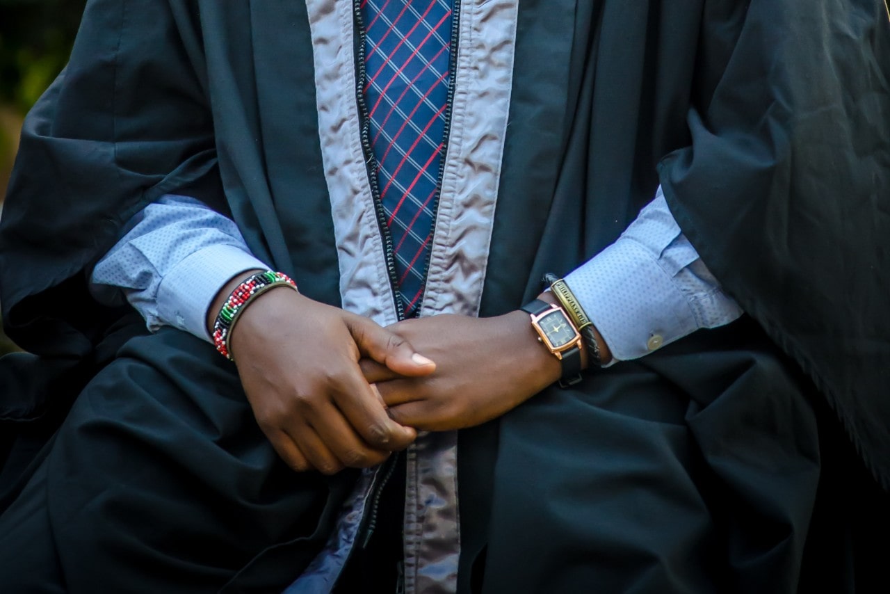 a graduate with their hands in their lap, wearing a tonneau shape watch