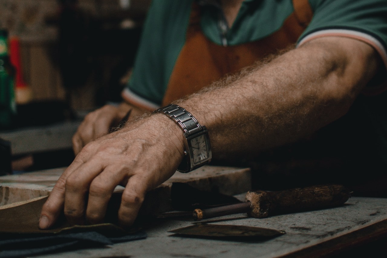 A man working in a workshop, wearing a watch with a rectangular case.