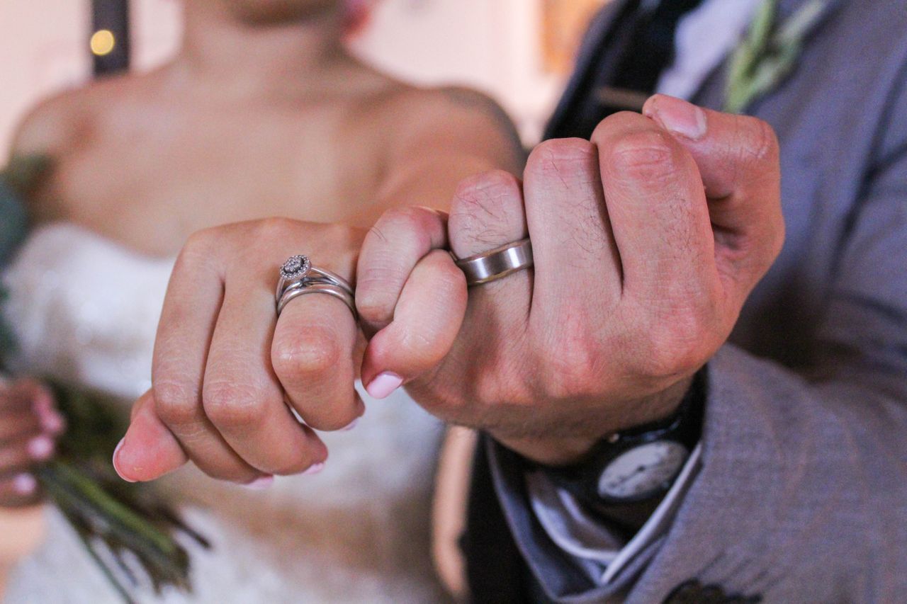 The bride’s and groom’s hands with the wedding bands on them