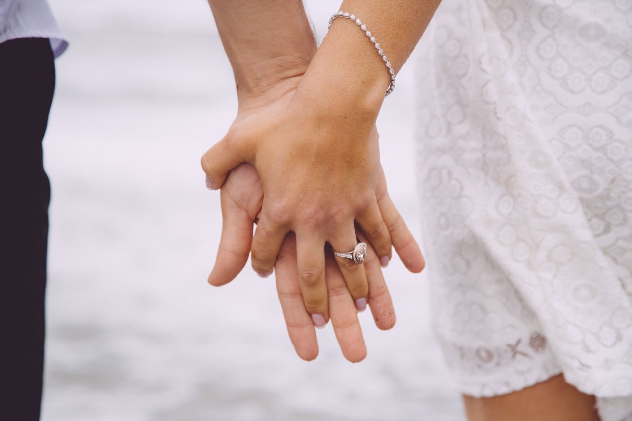 oval cut diamond ring with two hands holding