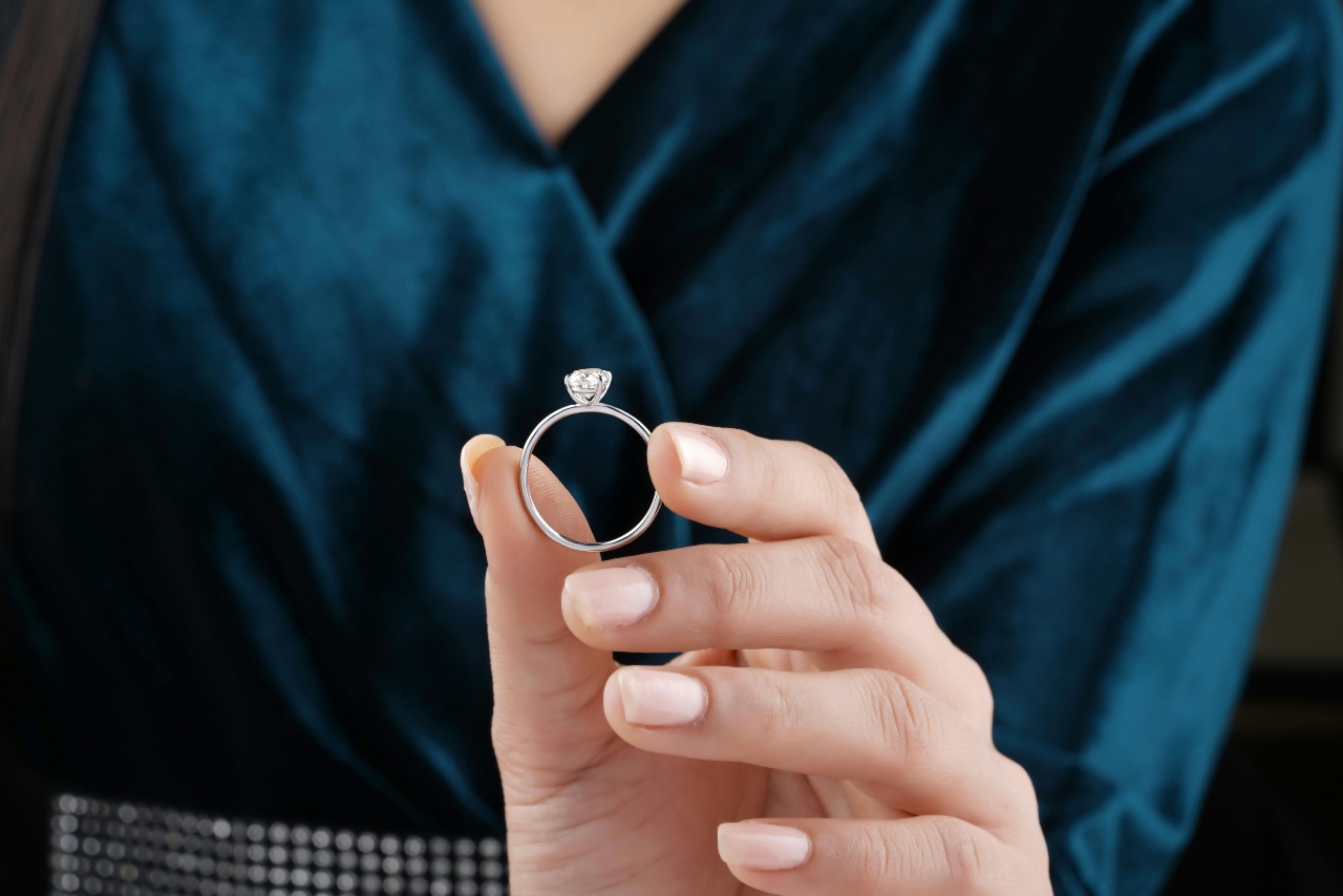 a lady holding a diamond earring in her hand