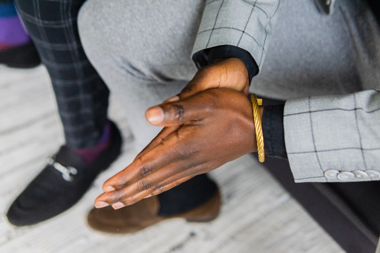 A well–dressed man wearing a gold bracelet on his left wrist.