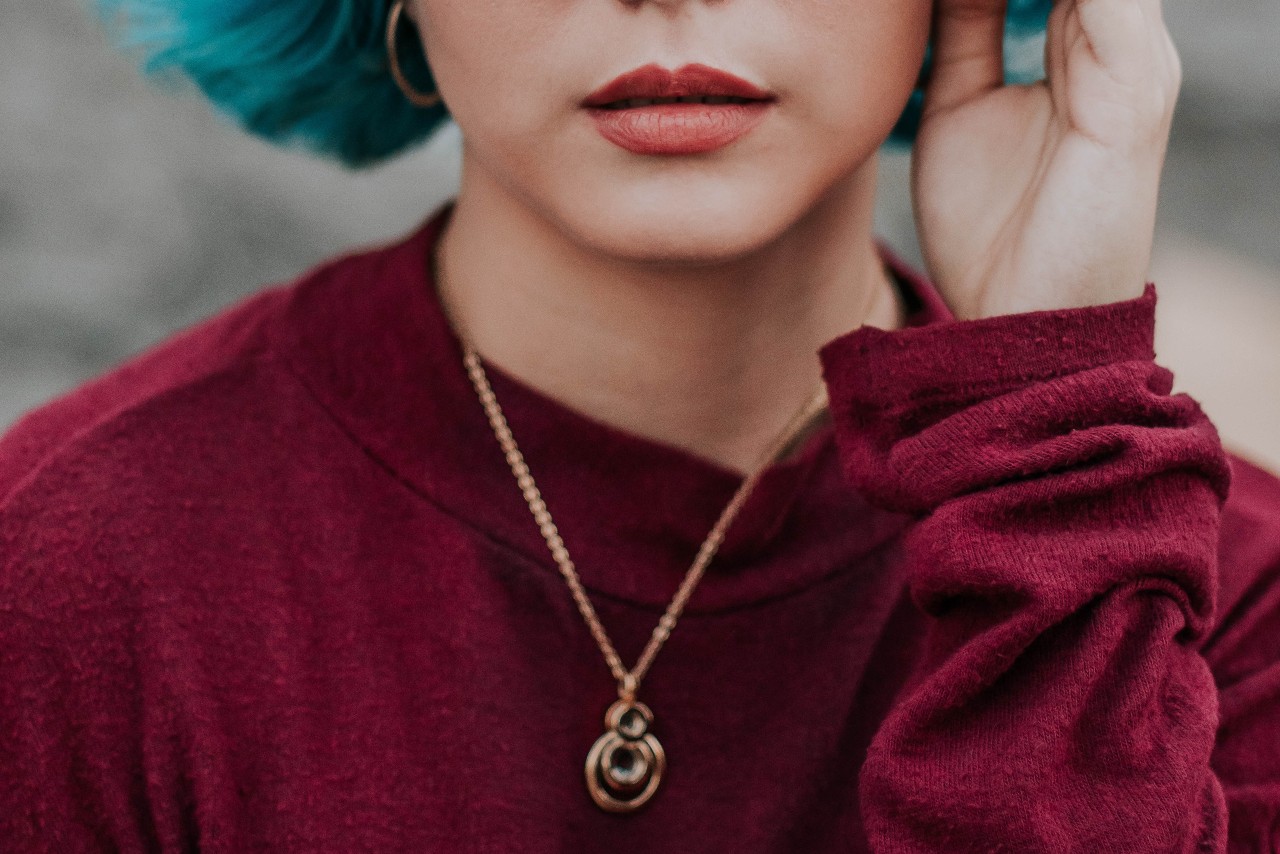 A trendy young woman wearing an ornate gold necklace.