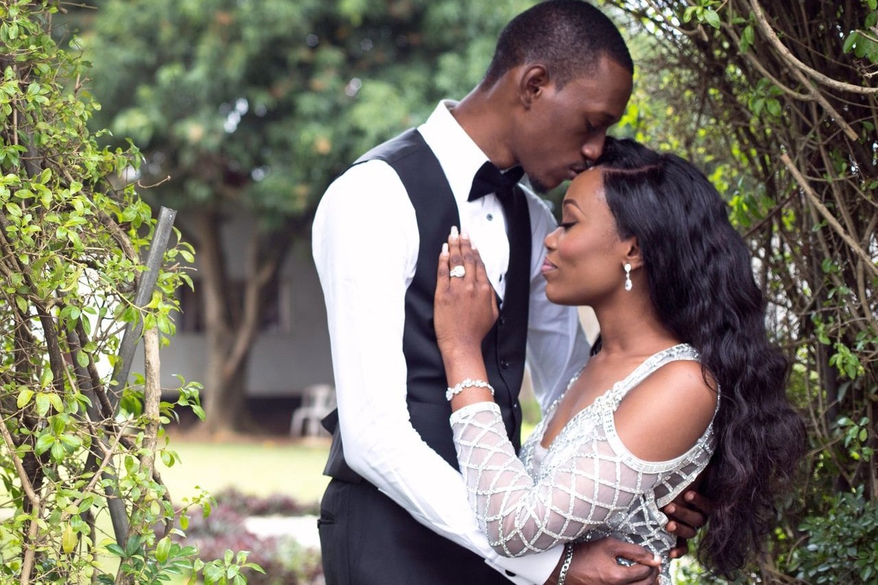 a bride and groom embracing outdoors near some trees