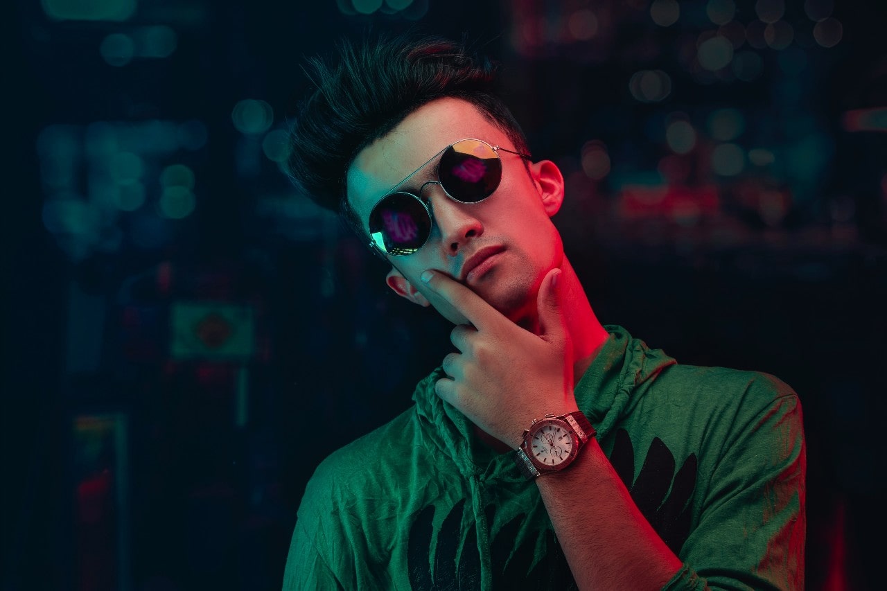 A man in a neon lit room poses while wearing a vintage watch.