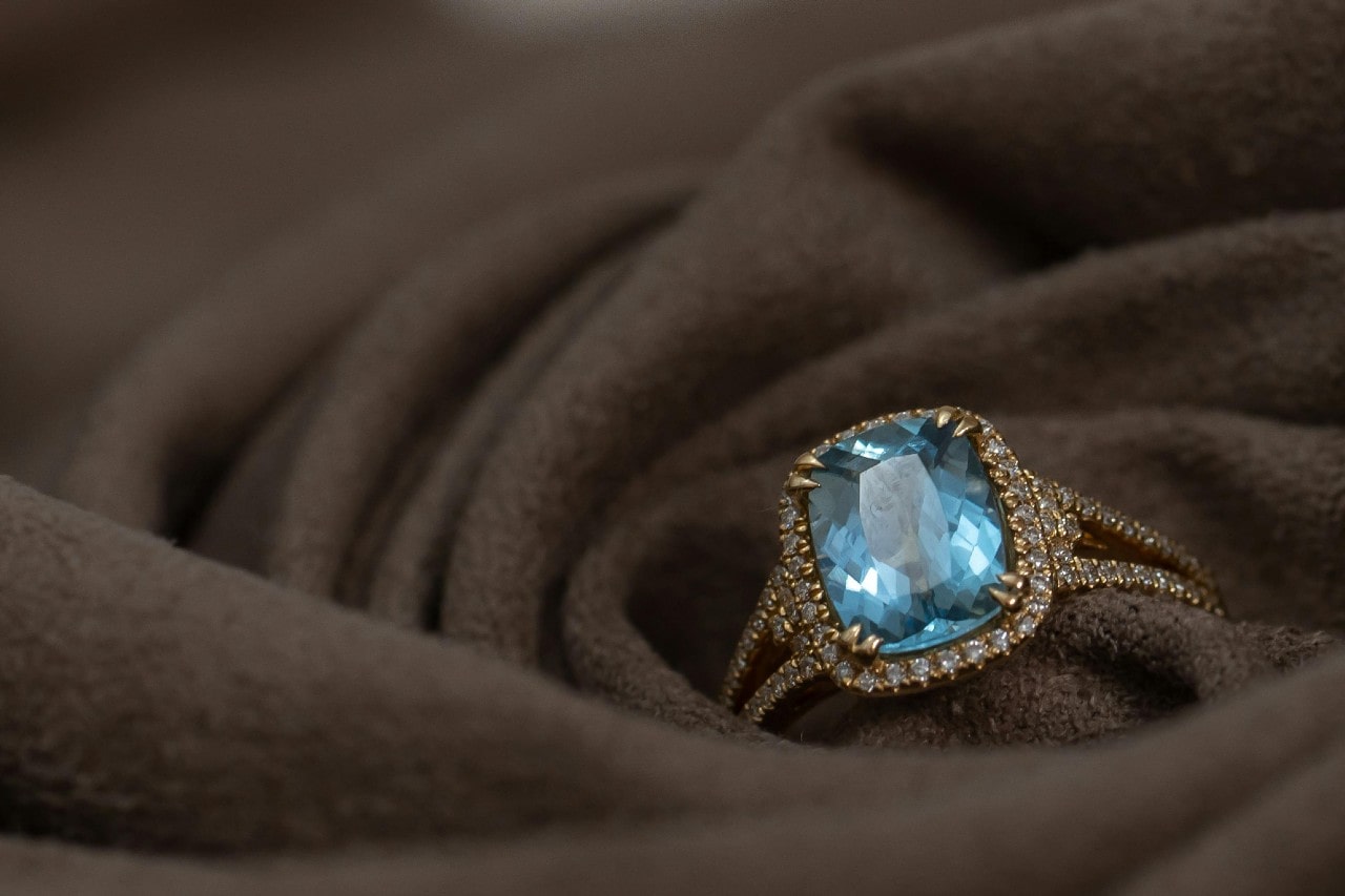 A close-up of a non-traditional engagement ring resting in a soft brown cloth.